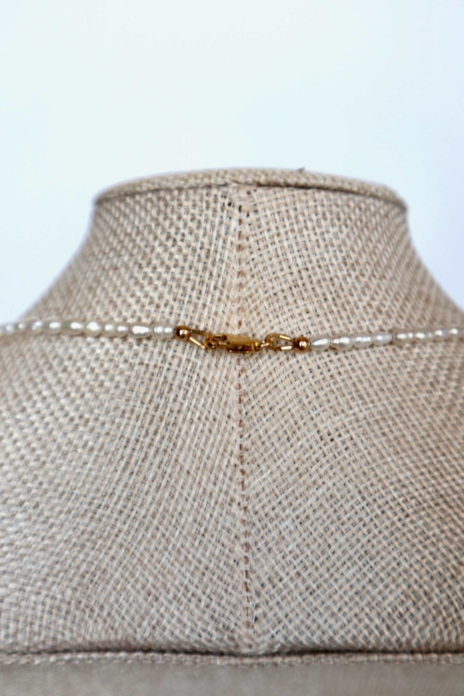 Auréad Designs Nacrine necklace back clasp detail showing 14k gold-filled lobster clasp with freshwater rice pearl strand on linen bust form
