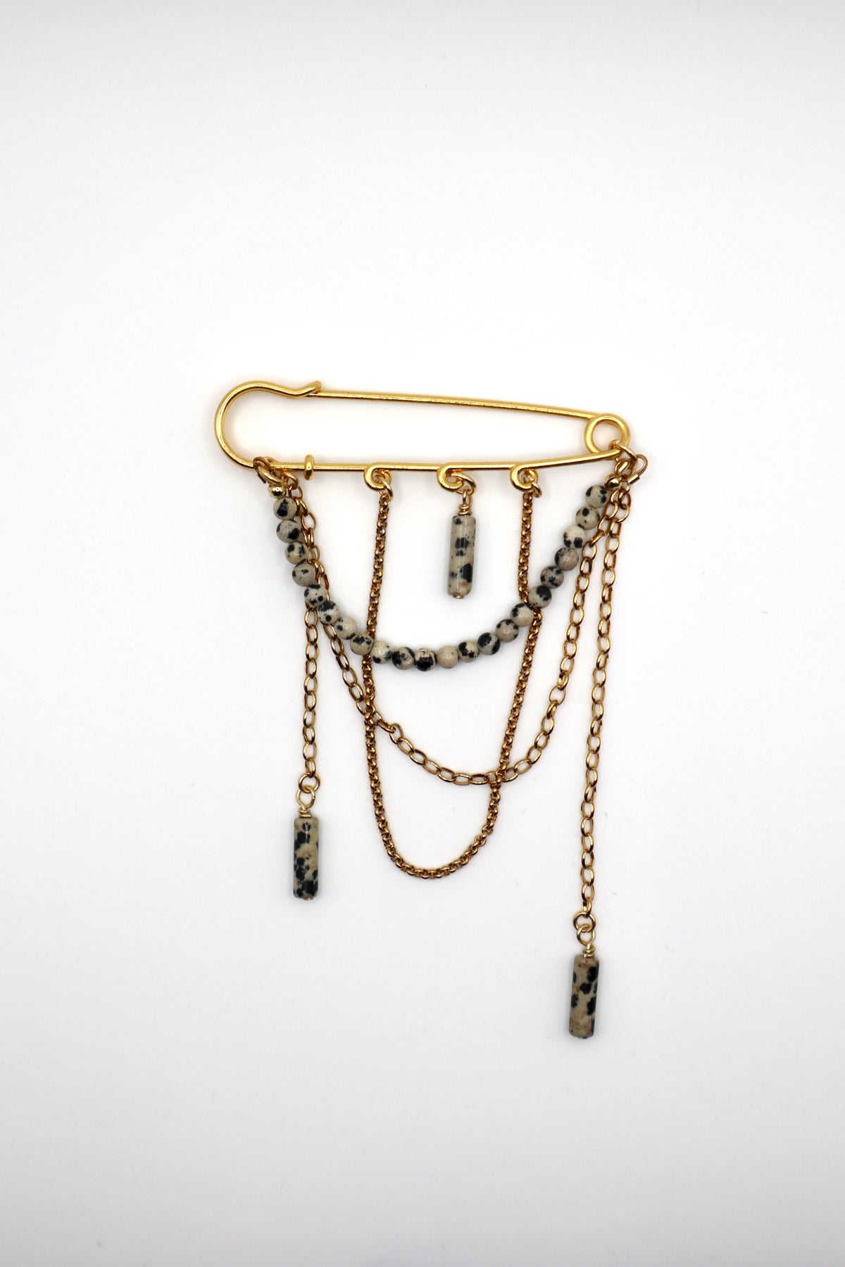 Perrin pin brooch by Auréad Designs showing the full design: Dalmatian jasper beads, safety pin-style closure, and cascading gold stainless steel chains