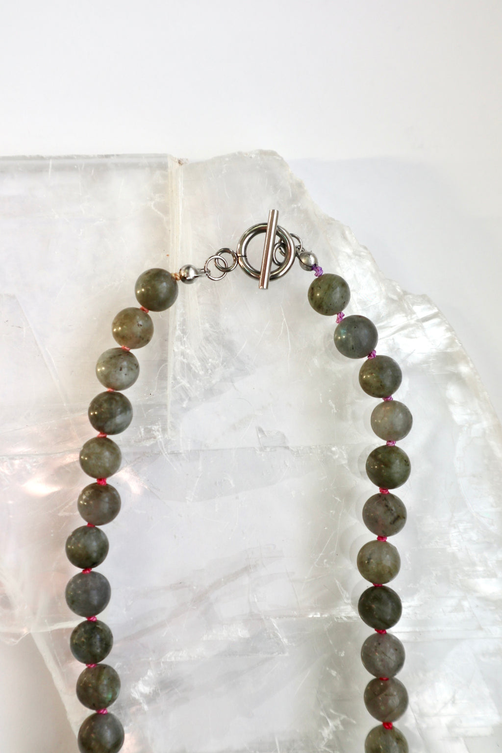 Close-up of the Prism necklace showing the spectral flash of labradorite beads and the multicolor ombré silk cord with its hand-finished artisanal character