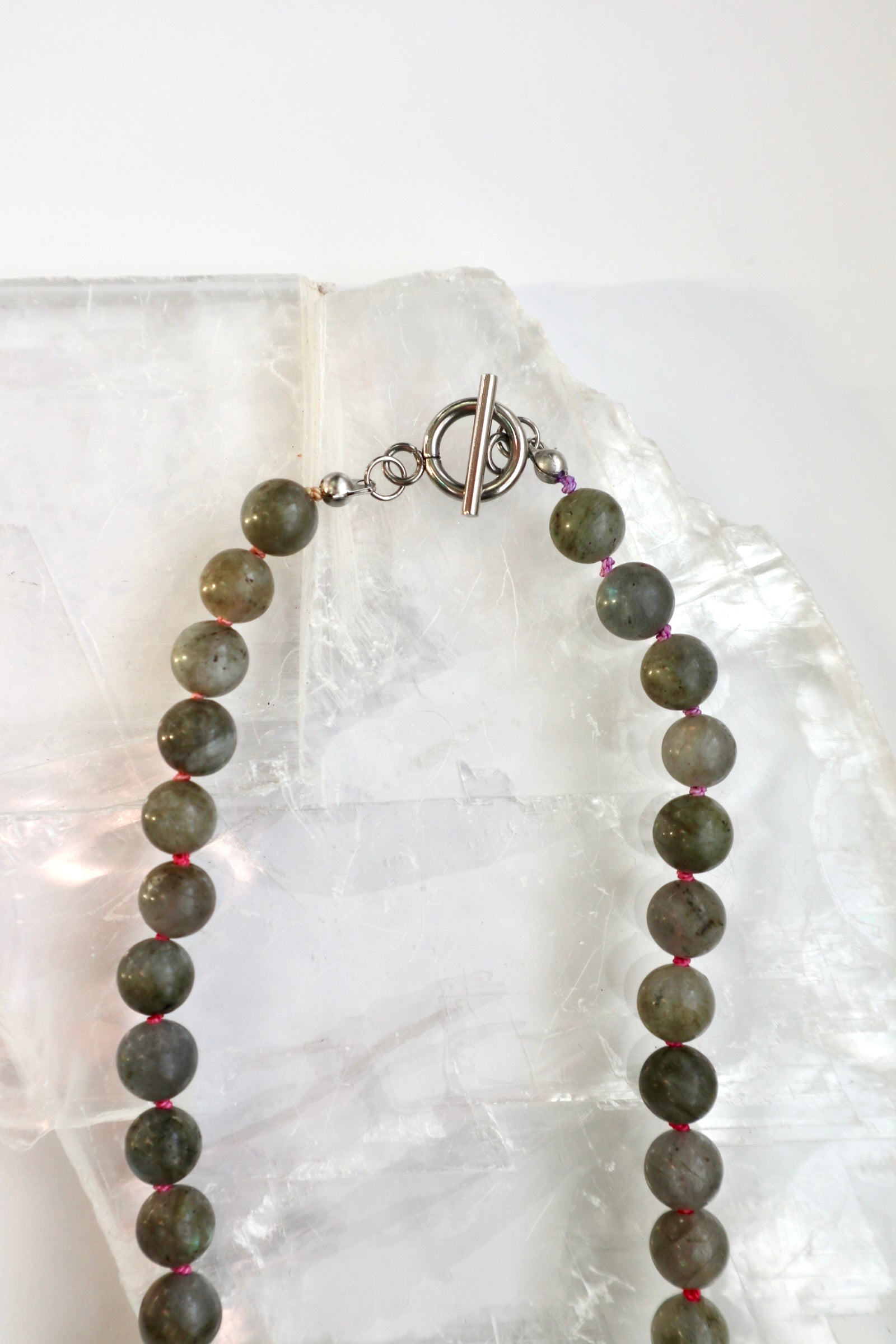 Close-up of the Prism necklace showing the spectral flash of labradorite beads and the multicolor ombré silk cord with its hand-finished artisanal character