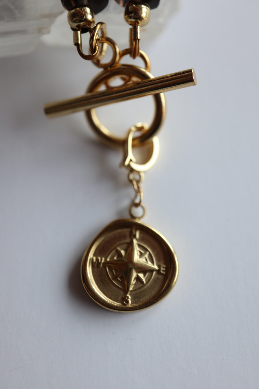 Close-up of the gold compass rose charm and toggle clasp on the Ridge necklace by Auréad Designs