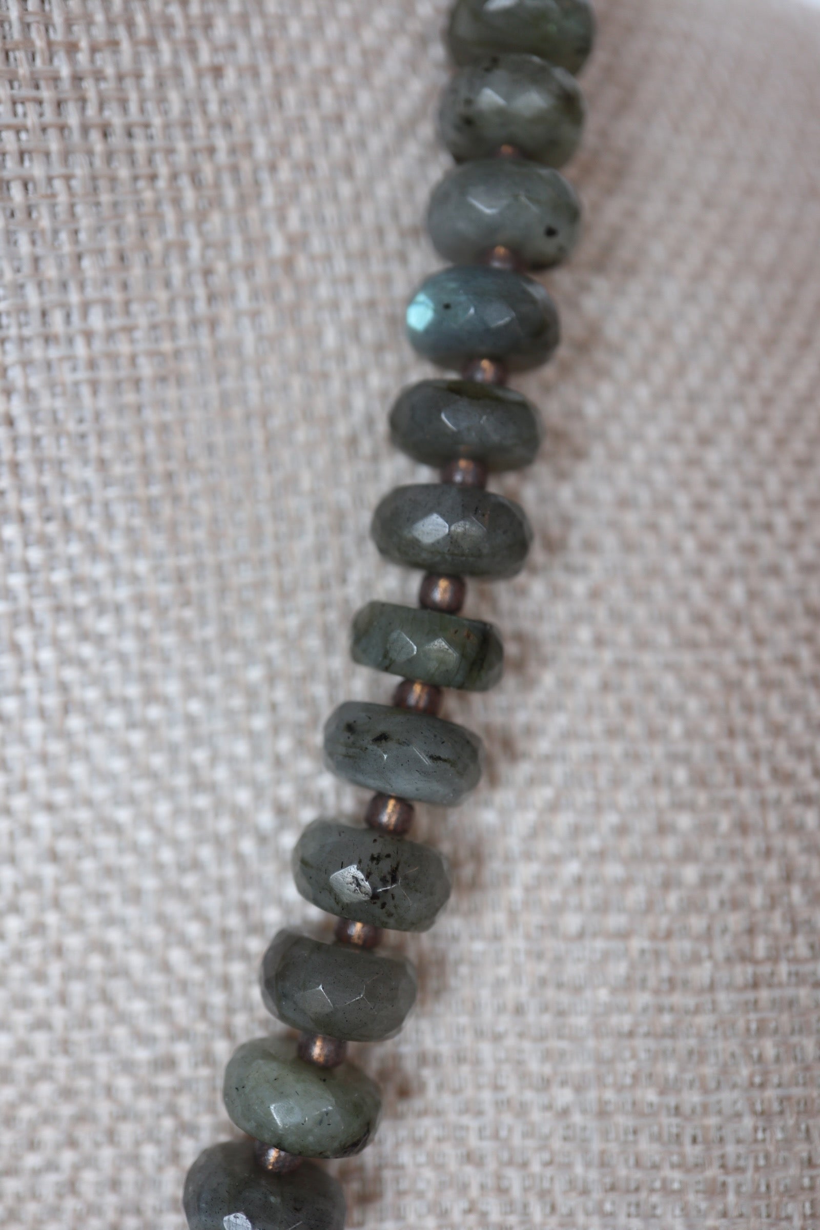Close-up of faceted labradorite rondelle beads on the Ridge necklace by Auréad Designs, showing the natural gray-green color and subtle flash of the stone
