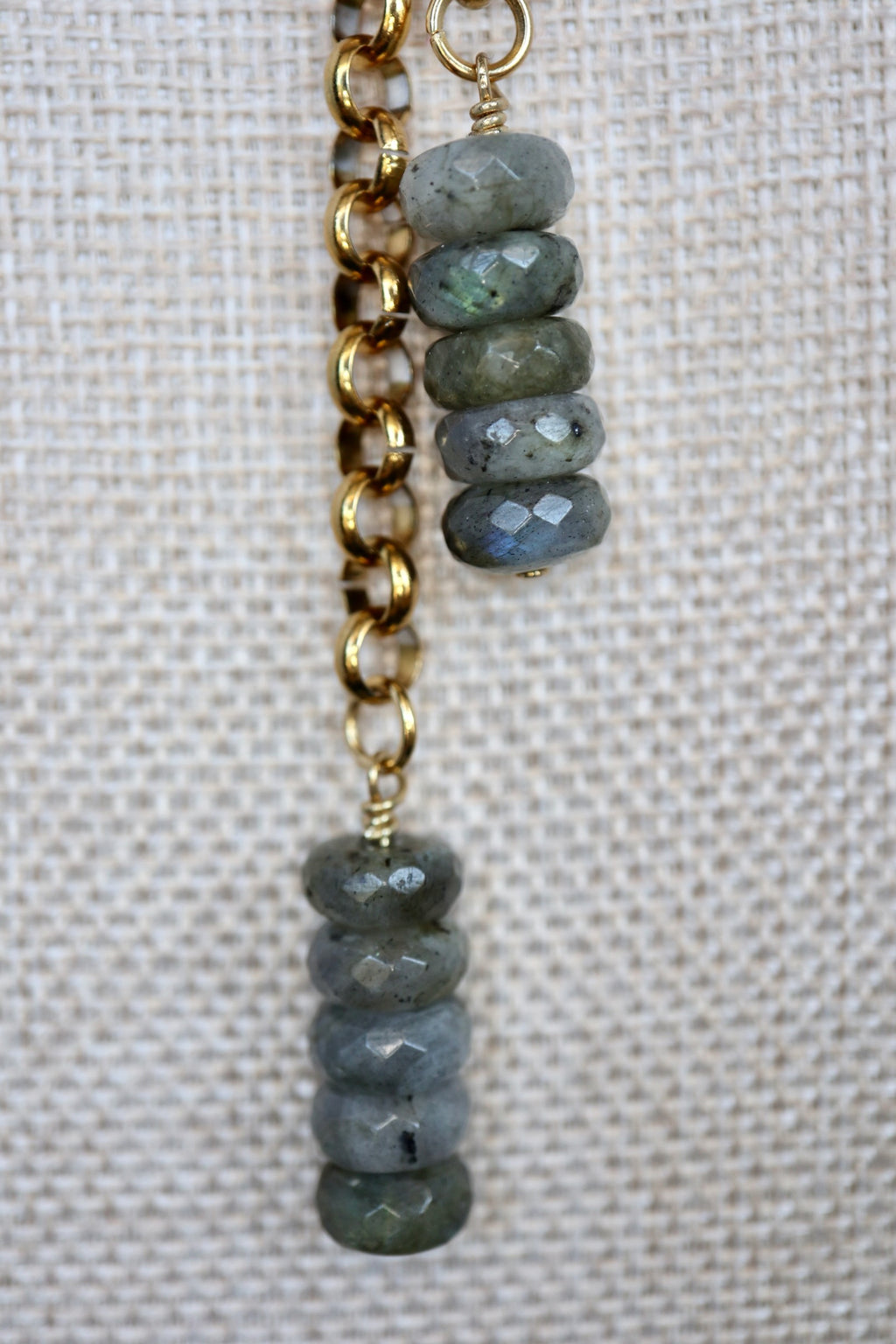 Close-up of Auréad Designs Rochelle dual labradorite faceted rondelle drop pendants on gold rolo chain, displayed on a linen bust form, showing blue flash in the stone.