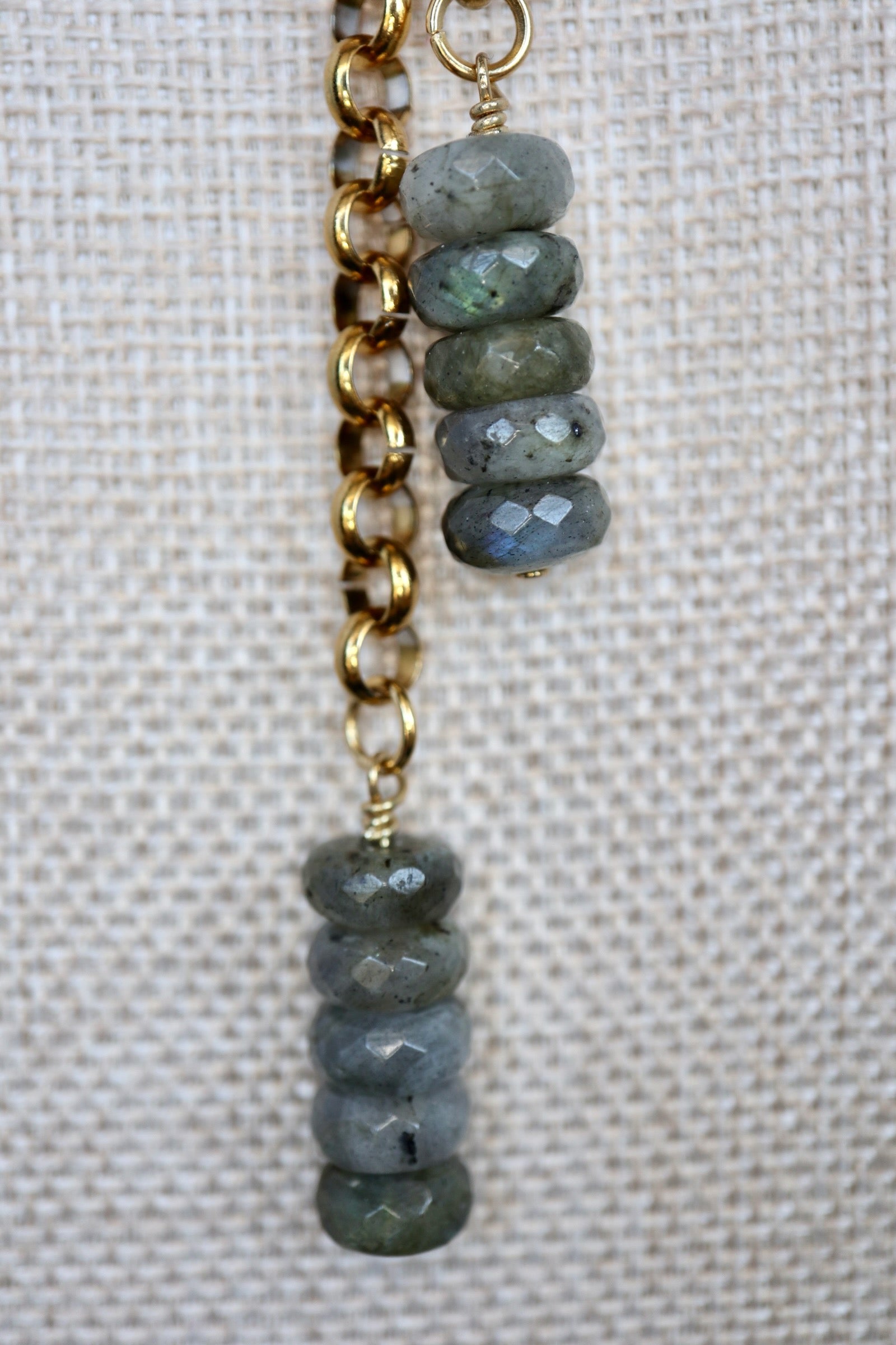 Close-up of Auréad Designs Rochelle dual labradorite faceted rondelle drop pendants on gold rolo chain, displayed on a linen bust form, showing blue flash in the stone.