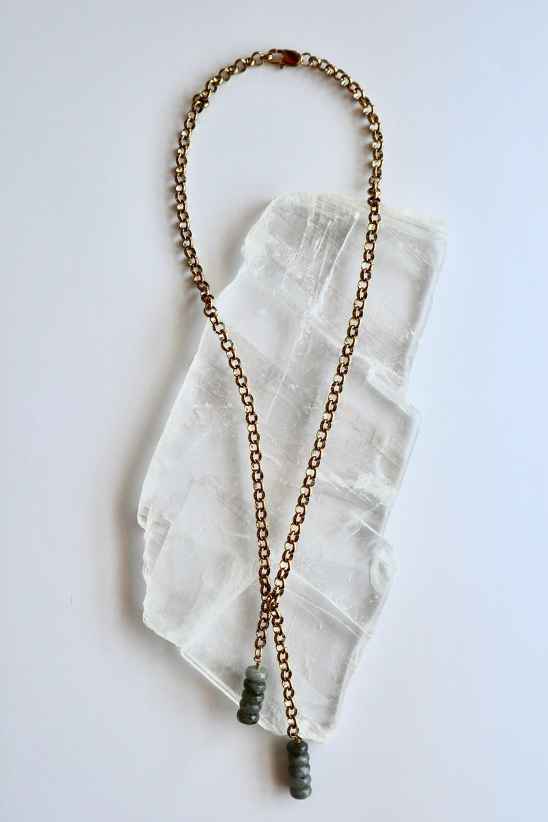 Auréad Designs Rochelle gold rolo chain lariat necklace with labradorite rondelle drop pendants, overhead flat lay on white selenite slab showing full 21-inch length.