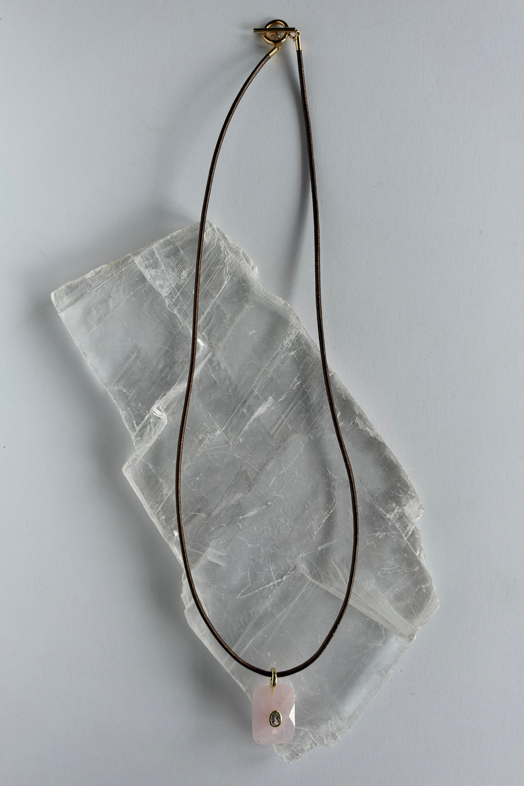Rosenne rose quartz faceted pendant necklace by Auréad Designs on white selenite slab, full length