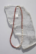 Rosera necklace by Auréad Designs, featuring rhodonite heishi beads, freshwater pearls, and galvanized gold spacer beads with a 14k gold-filled lobster clasp, laid flat on a white selenite slab
