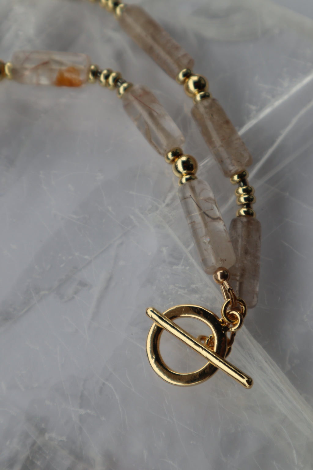Detail shot of the Rutila necklace highlighting the gold-filled toggle clasp and the natural golden inclusions in the rutilated quartz cylinder beads