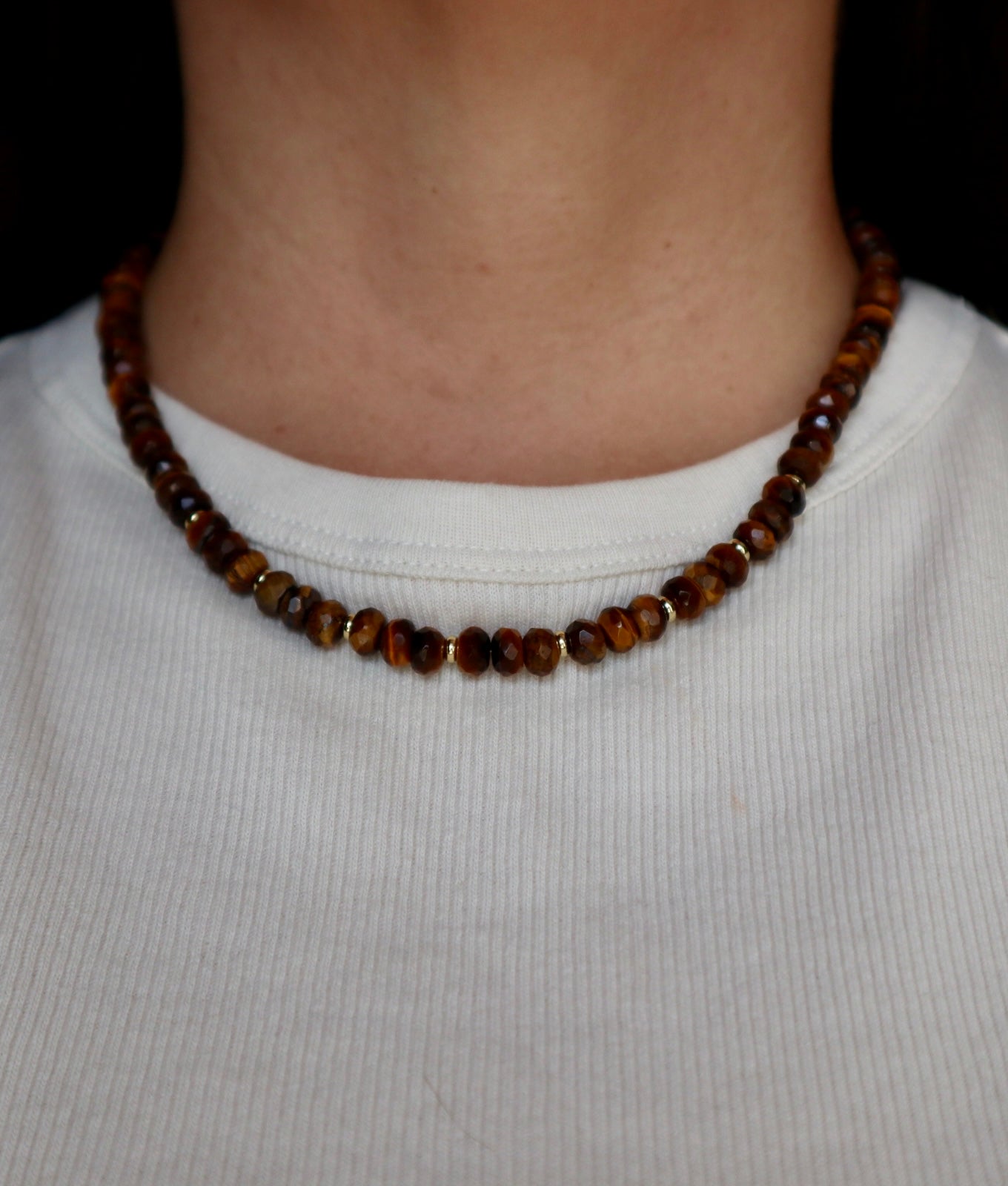 Sable necklace by Auréad Designs worn at the collarbone, styled with a white ribbed top, showing the full tiger eye and gold-filled bead strand with toggle clasp at the back