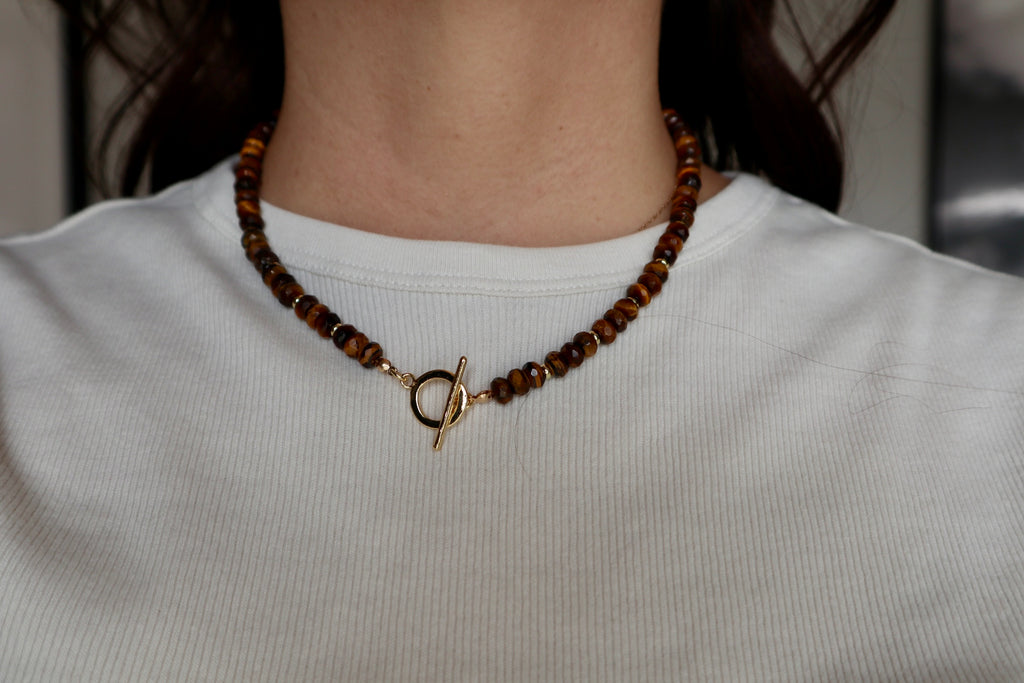 Sable tiger eye necklace worn on model with the gold-filled toggle clasp worn at the front as a styling detail, paired with a simple neckline