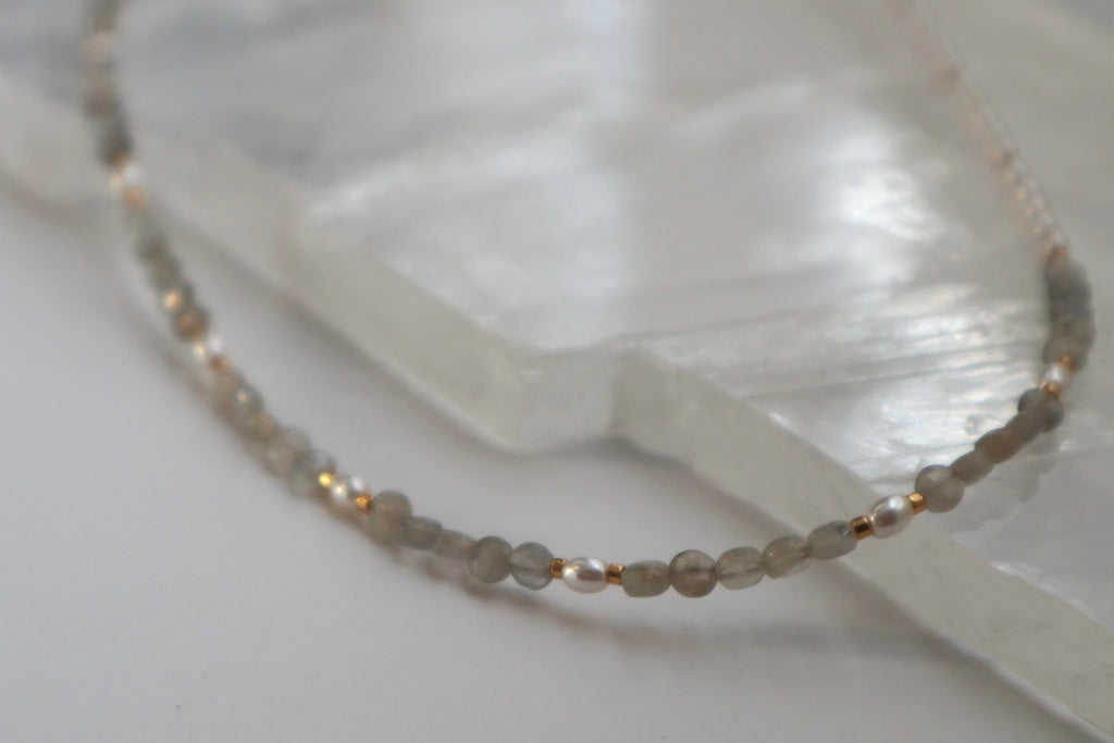 Close-up of the Selene necklace showing the spectral blue, green, and teal flash of faceted labradorite beads alongside the soft luster of glass pearls