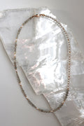 Selene necklace by Auréad Designs, featuring faceted labradorite beads and glass pearls with a 14k gold-filled clasp, laid flat on a white selenite slab