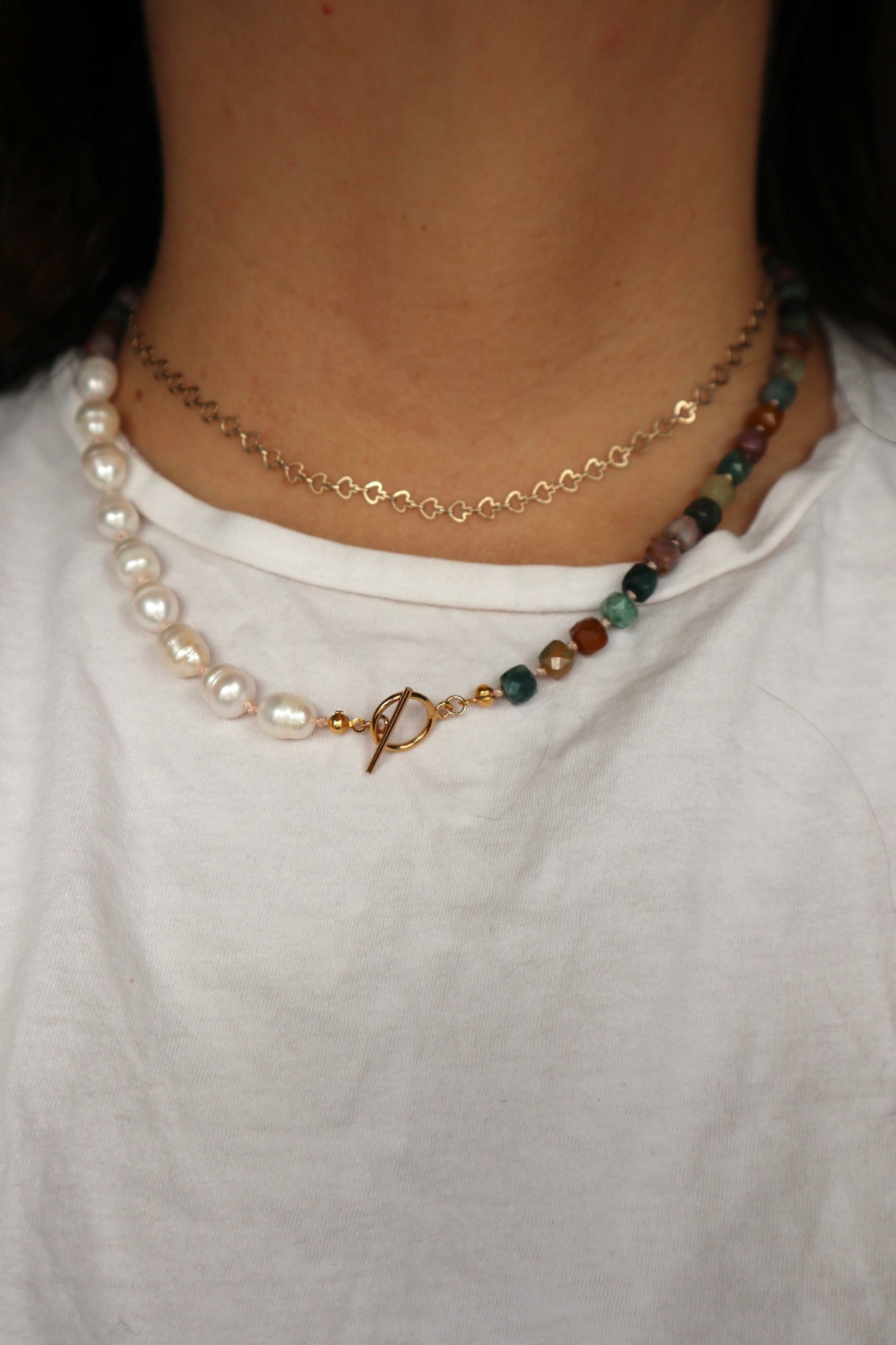 Angled view of the Siena necklace worn close to the neckline, showcasing the natural color variation of Indian agate alongside the luminous freshwater pearls and gold toggle clasp