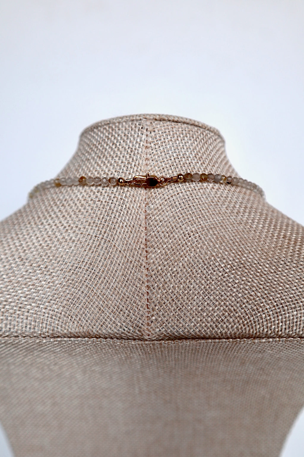 Close-up of the gold lobster clasp on the Snow necklace by Auréad Designs