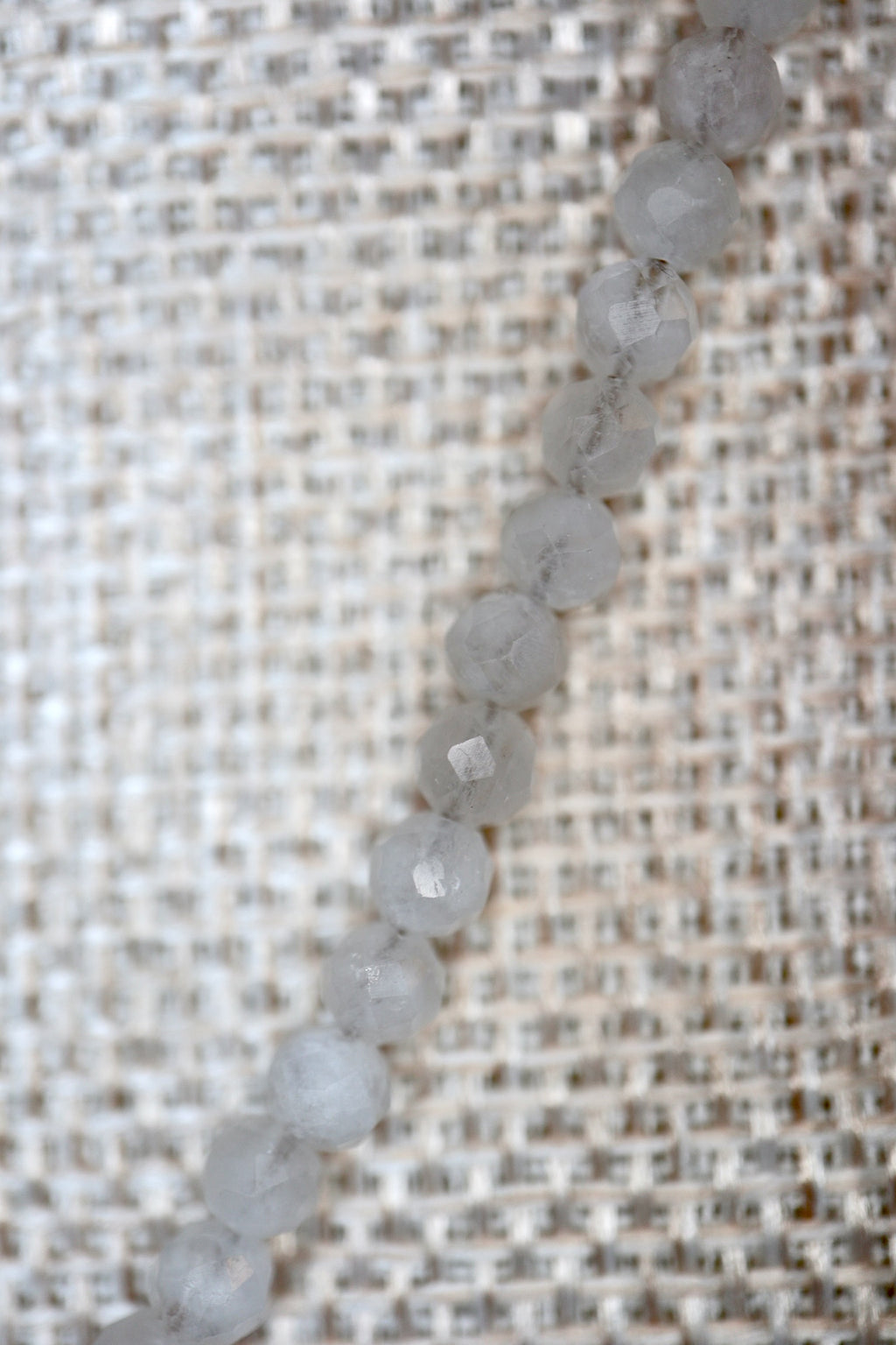 Close-up of faceted rainbow moonstone rondelle beads on the Snow necklace by Auréad Designs, showing the stone's soft white color and subtle shimmer
