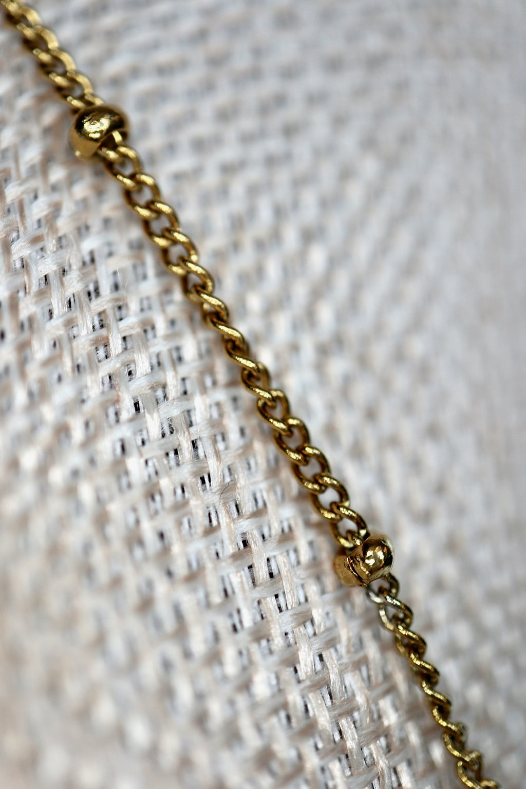 Close-up of the gold satellite chain with small gold bead accents on the Snow necklace by Auréad Designs