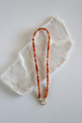Solara necklace by Auréad Designs, featuring orange aventurine gemstone beads and gold-filled toggle clasp, laid flat on a white selenite slab