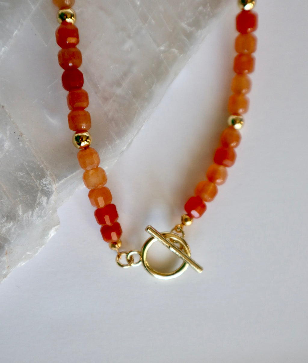 Close-up of the Solara necklace showing vibrant orange aventurine beads and a gold-filled toggle clasp with gold spacer beads