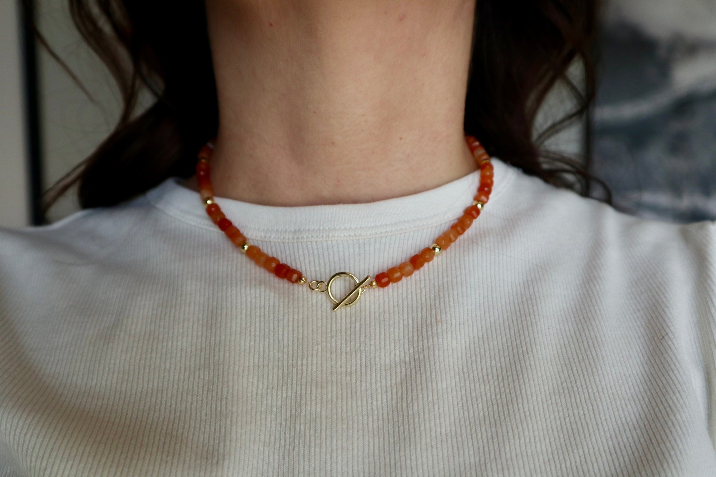 Close-up of the Solara necklace resting at the collarbone, highlighting the warm luminous tones of orange aventurine beads and gold-filled toggle