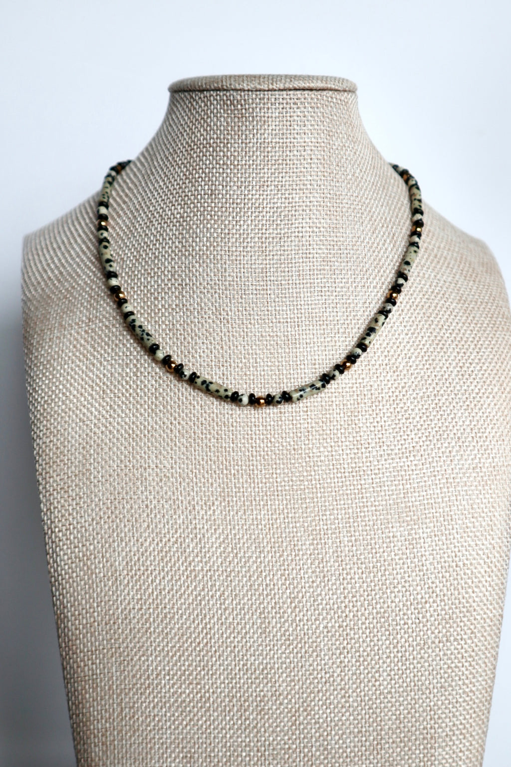 Sorren necklace by Auréad Designs displayed on a linen bust form, showing the full beaded strand of dalmatian jasper and ice obsidian