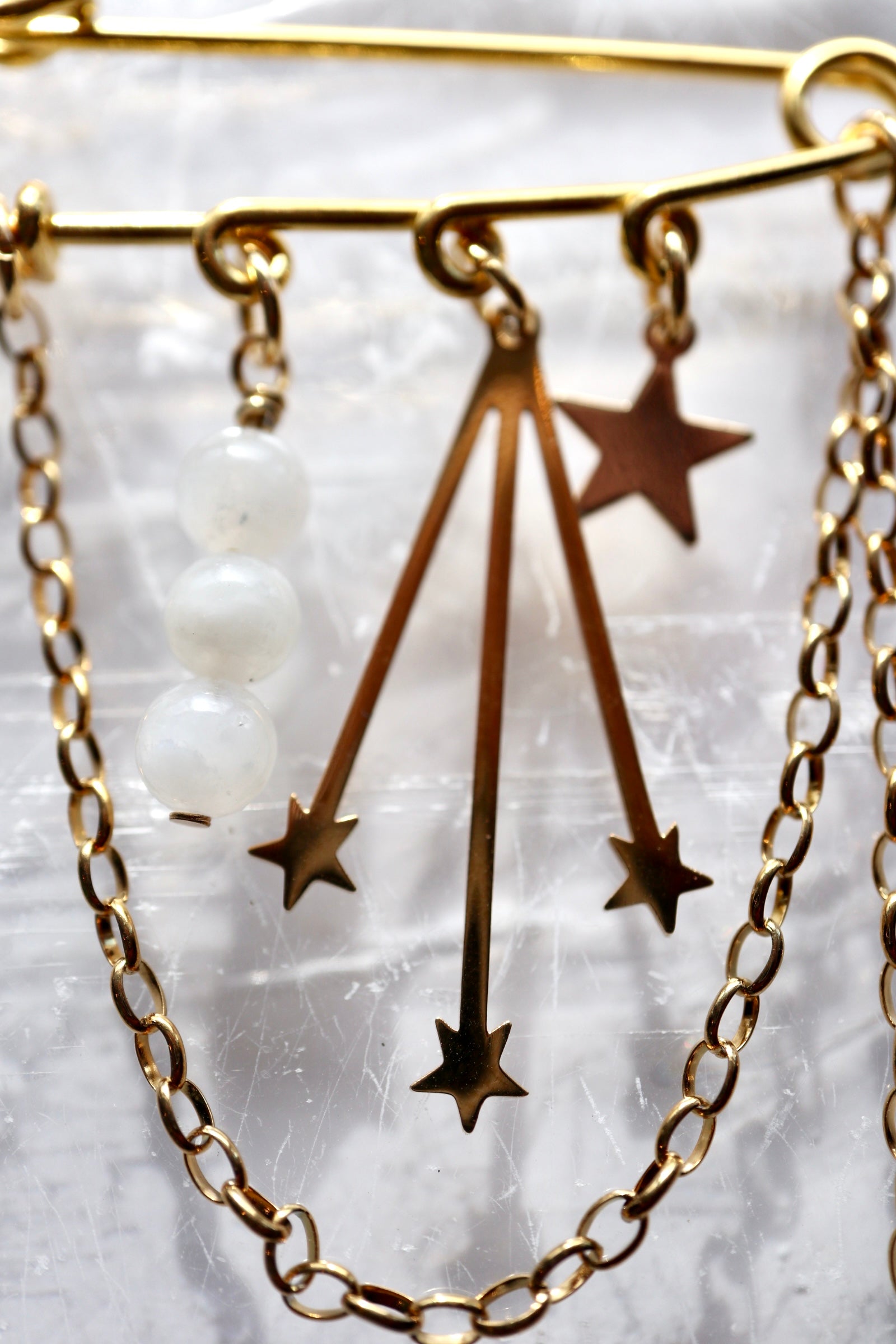 Detail shot of the Stellune brooch, highlighting the gold stainless steel star and celestial charms alongside moonstone beads