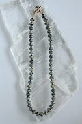 Tessere Dalmatian jasper and hematite beaded necklace by Auréad Designs on white selenite slab
