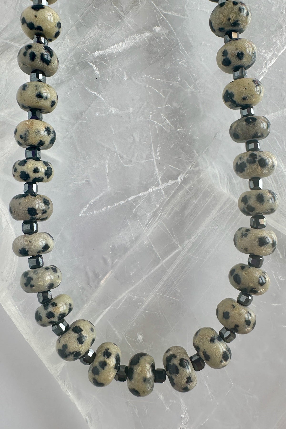 Tessere Dalmatian jasper and hematite necklace by Auréad Designs, close-up showing bead pattern on selenite slab
