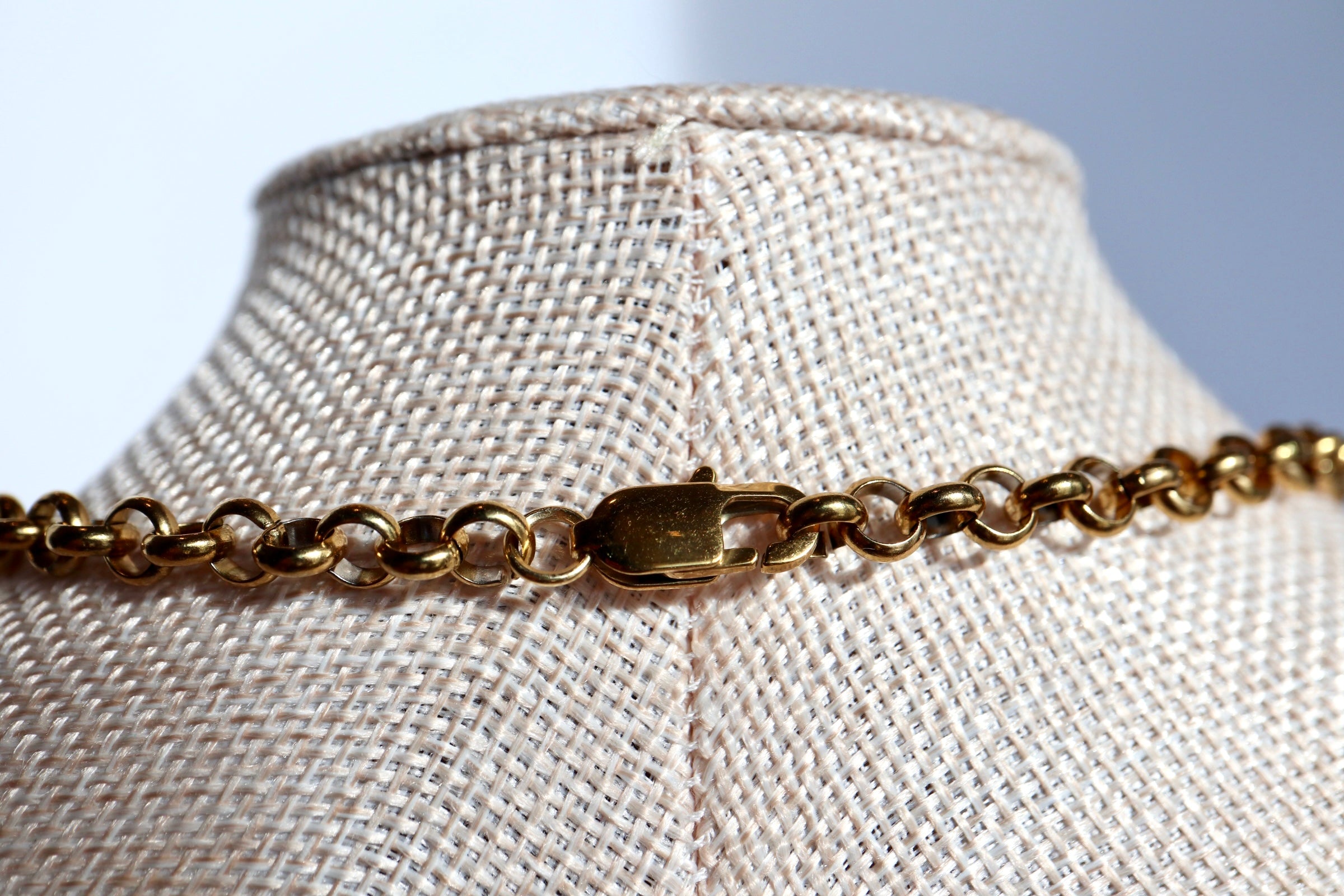 Umbra necklace by Auréad Designs resting on a linen bust form, highlighting the gold stainless steel rolo chain and lobster clasp