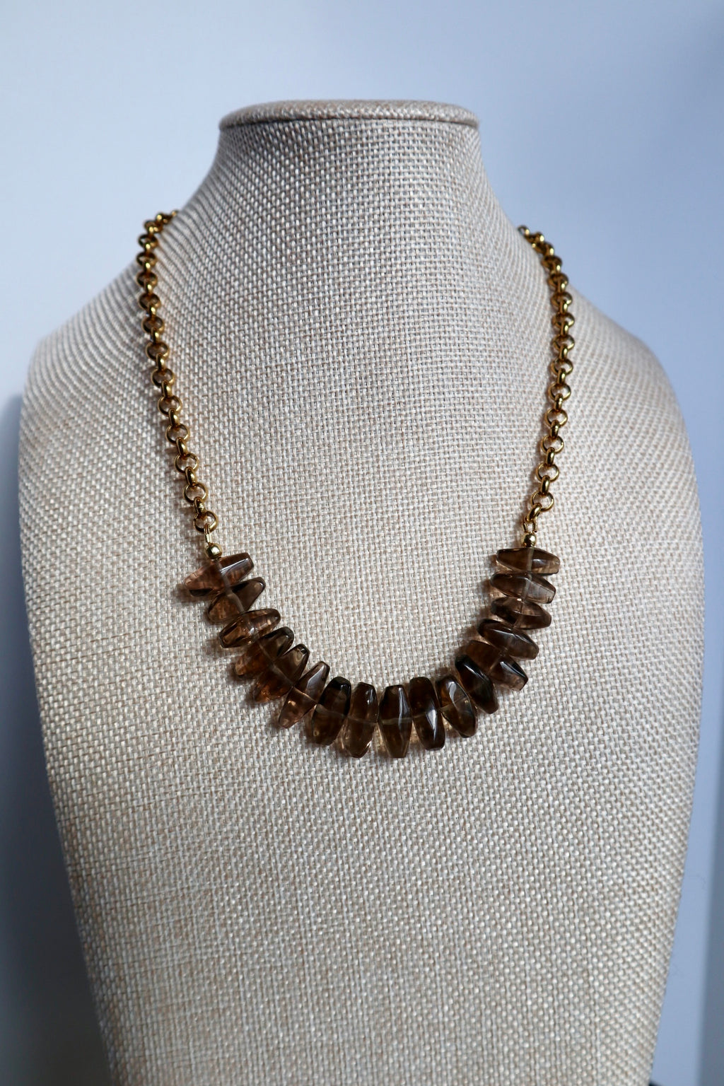 Umbra smoky quartz and gold rolo chain necklace displayed on a linen bust form, front view showing the full beaded drop arrangement