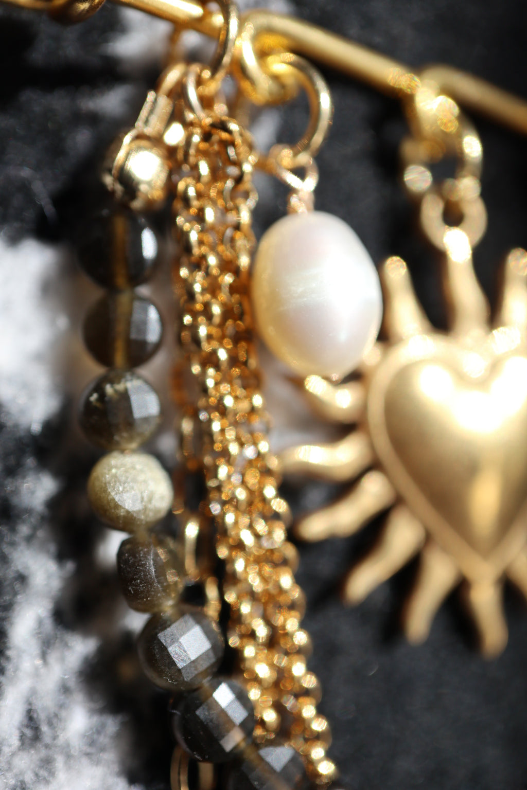 Close-up detail of the Velora brooch showing layered gold stainless steel chains, a gold heart charm, and a freshwater pearl drop