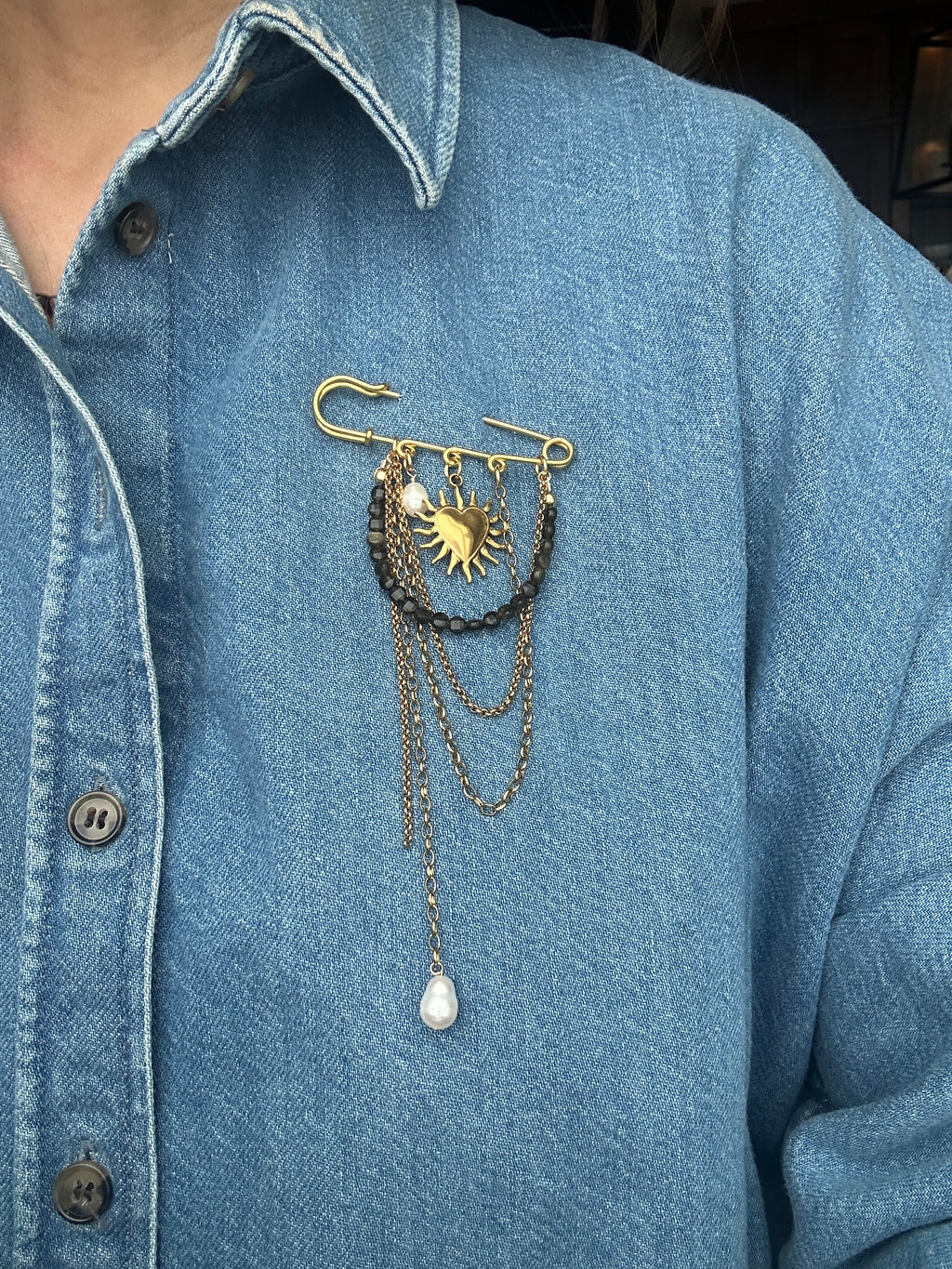 Velora pin brooch by Auréad Designs worn on a denim jacket lapel, showcasing gold sheen obsidian, pearl, and draped gold chains