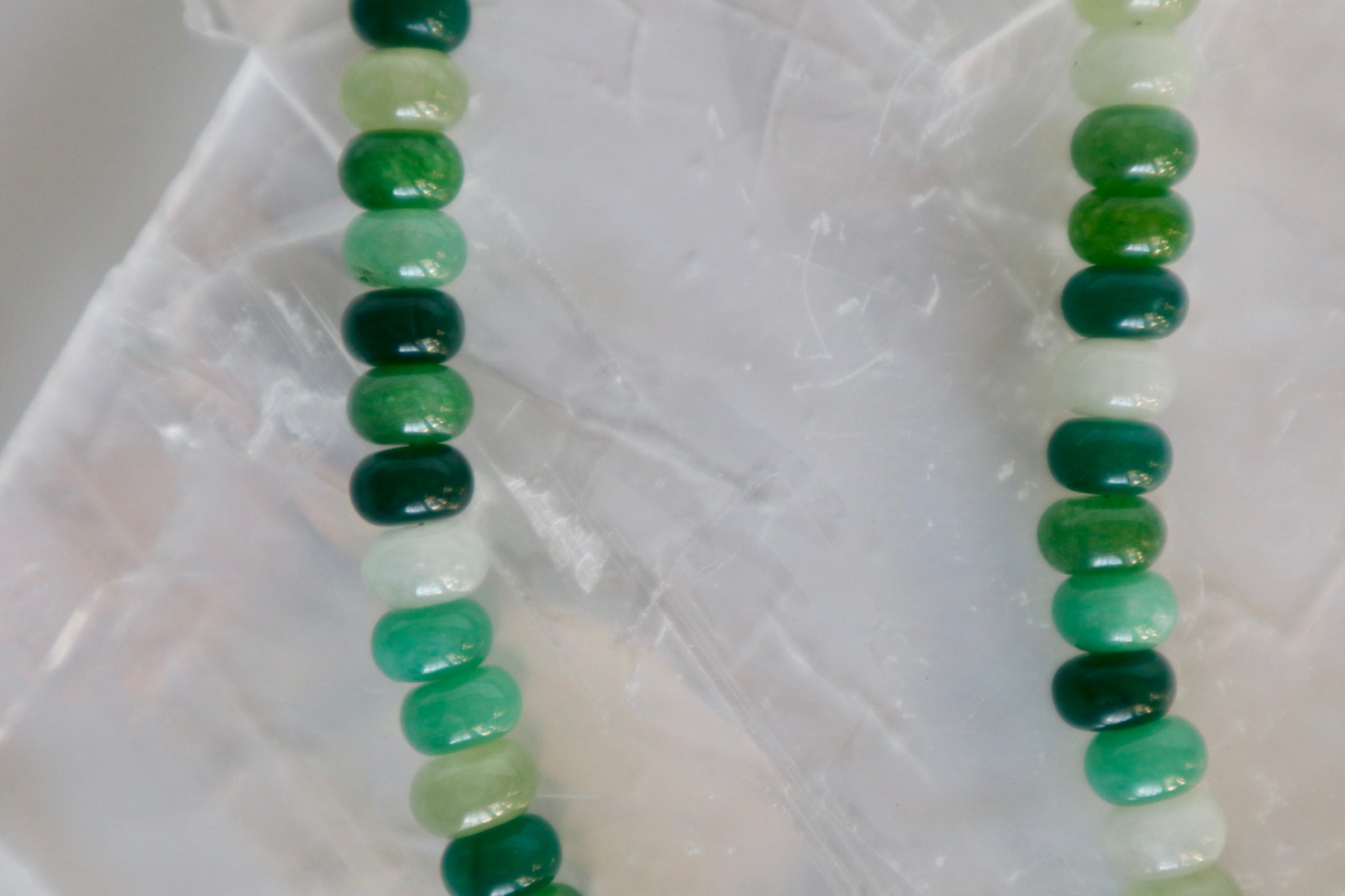 Detailed close-up of Verdelle necklace beads, highlighting the varying tones of green jade