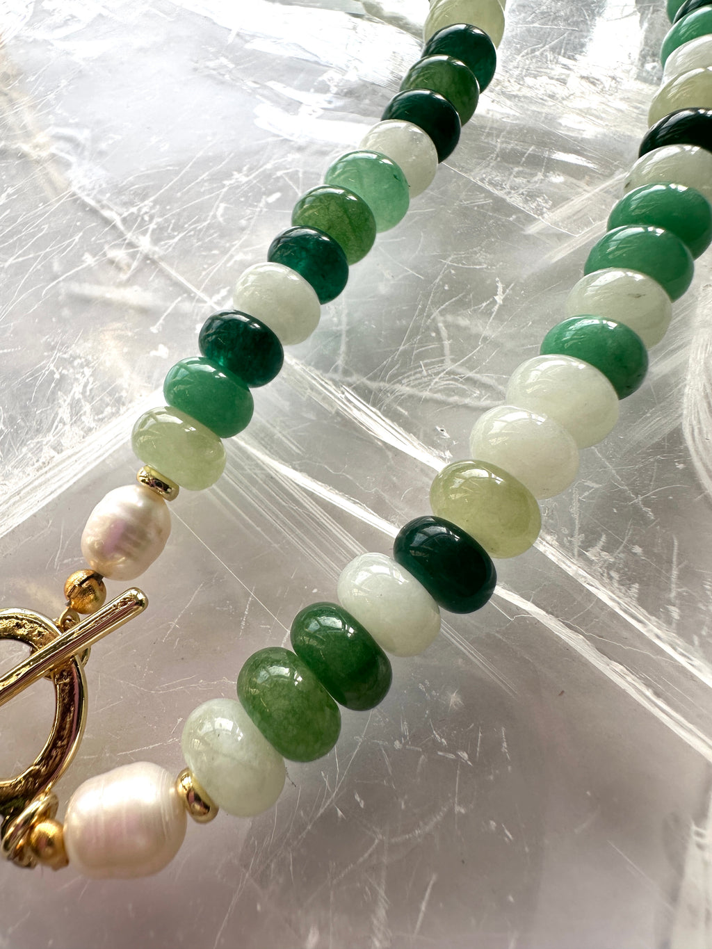 Detailed close-up of Verdelle necklace beads, highlighting the varying tones of green jade alongside cream freshwater pearls