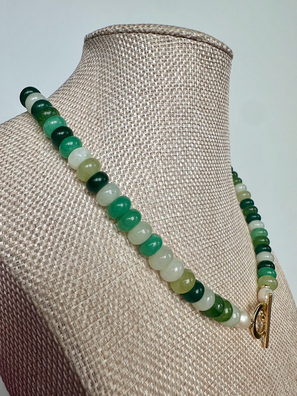 Side view of the Verdelle jade and freshwater pearl necklace on a linen bust form, with gold toggle clasp and pearl detail visible at the front