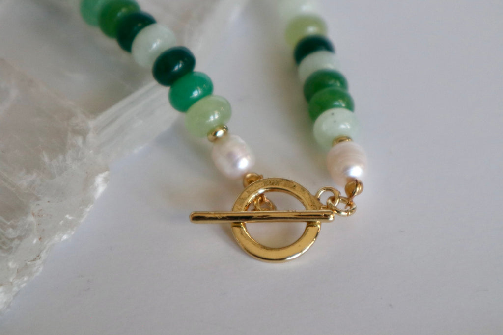 Close-up detail of the Verdelle necklace showing jade and freshwater pearl beads beside a gold toggle clasp