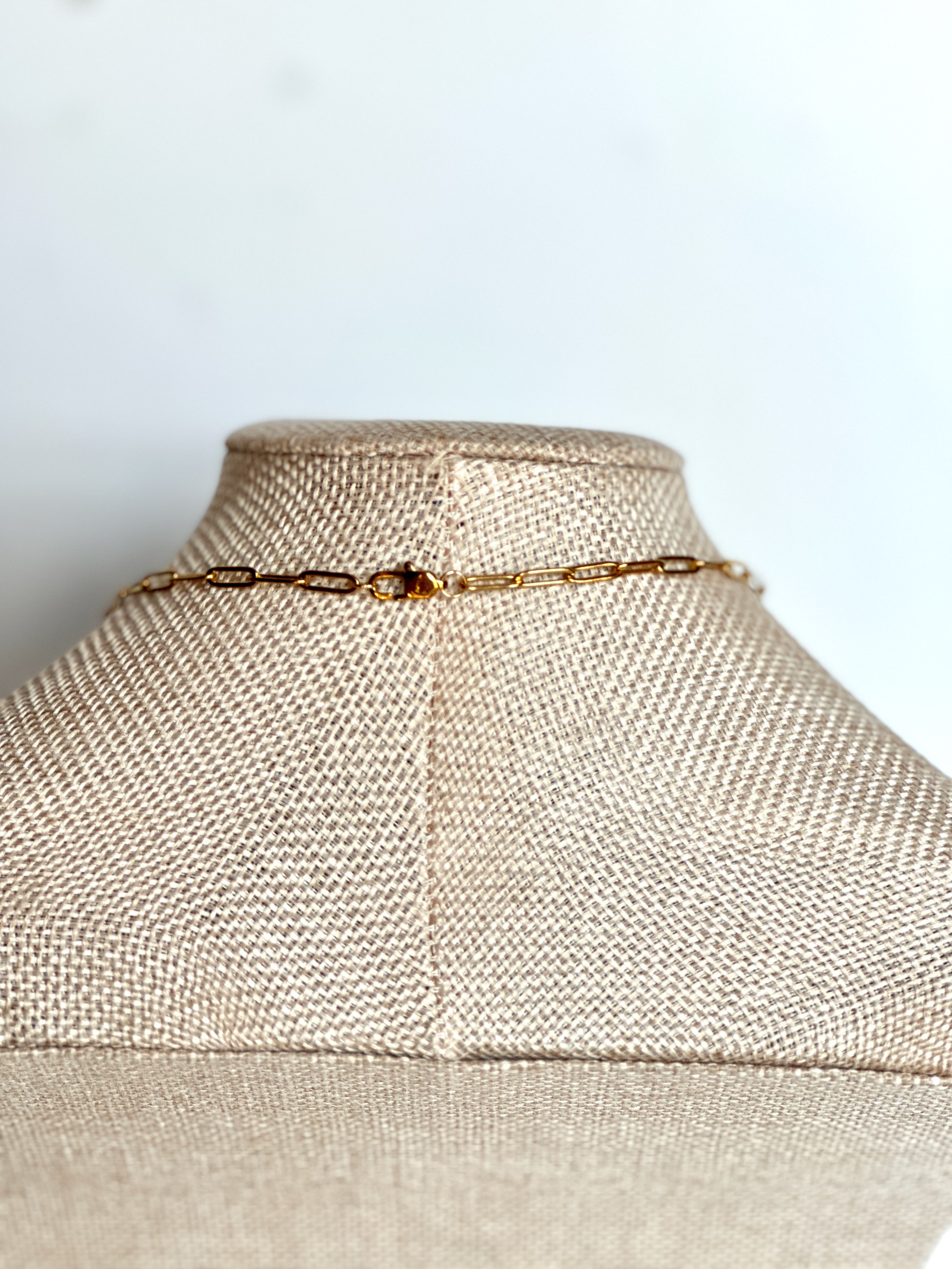 Close-up of the gold lobster clasp on the Wildflower necklace by Auréad Designs, showing the clasp and paperclip chain construction at the neckline