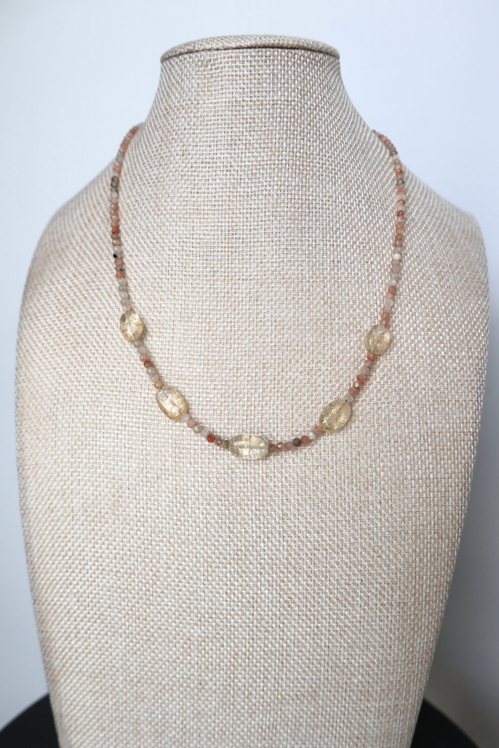Calora sunstone and citrine necklace displayed on a linen jewelry bust, full view showing five oval citrine beads evenly spaced along the strand
