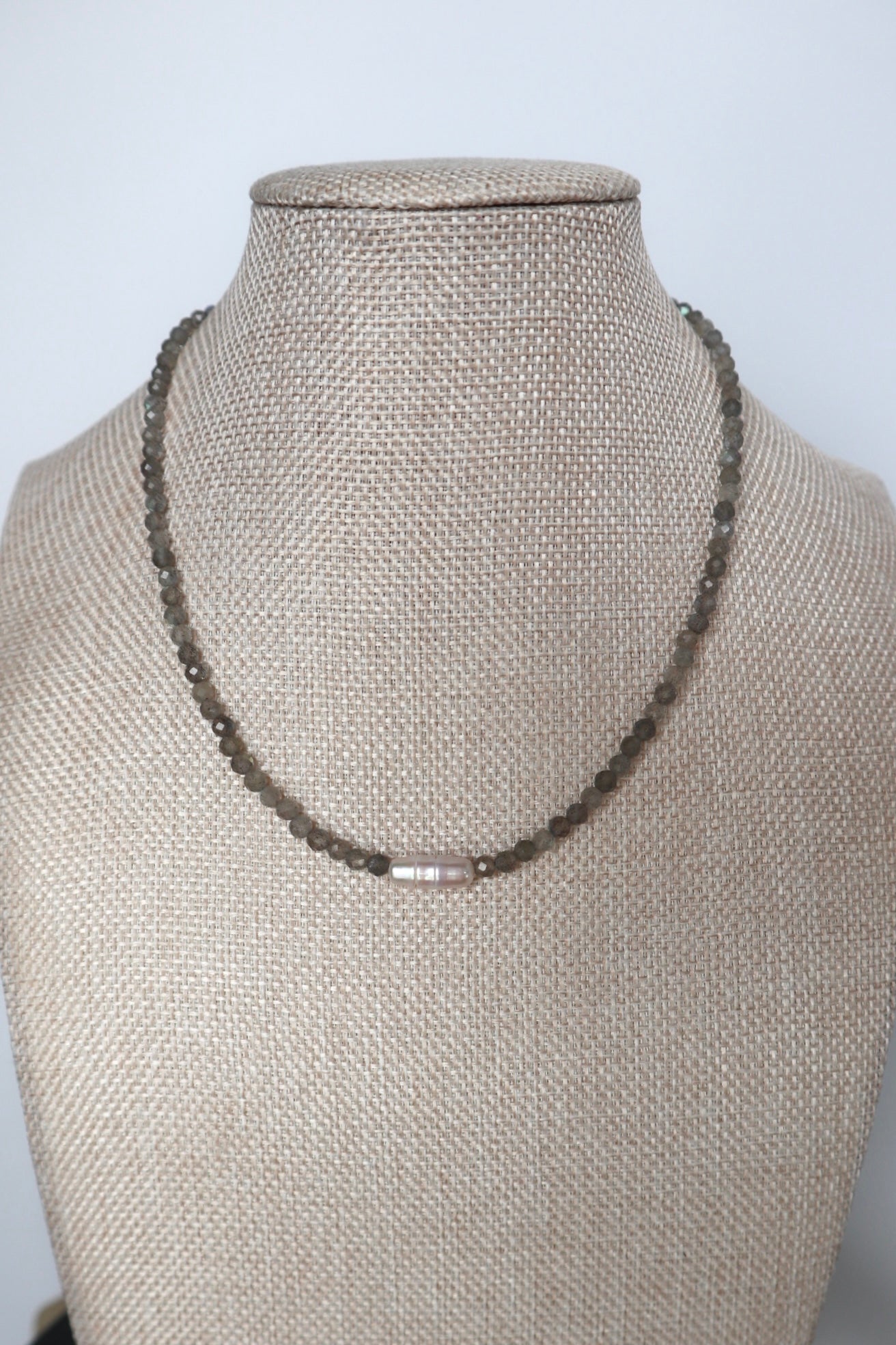 Liora labradorite and pearl necklace displayed on a linen jewelry bust, full collar view showing the pearl centerpiece and even bead spacing