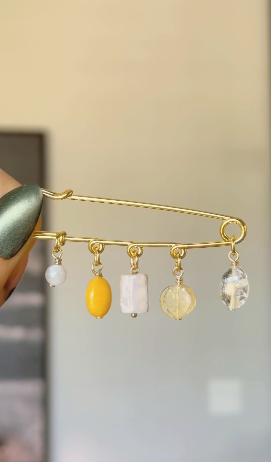 Video shows the Aurene gold kilt pin brooch with rainbow moonstone, yellow jade, cherry blossom agate, citrine, and clear quartz charm drops.